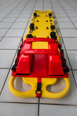 Lifeguard spineboard on white titles in swimming pool
