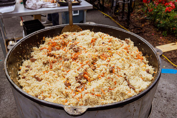 Cooking delicious traditional Uzbek pilaf in cauldron