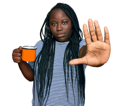 Young black woman with braids drinking a cup coffee with open hand doing stop sign with serious and confident expression, defense gesture