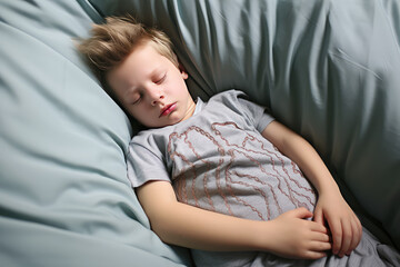Child sleepy boy is sad lying on the bed and holding his stomach. Abdominal pain in children, symptoms of gastritis, poisoning and intestinal infection, abdominal bloating. - Powered by Adobe