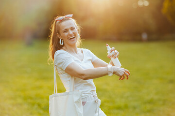 happy stylish woman in white shirt using sunscreen