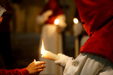 A Nazarene on an Easter night with a candle and a child's hand