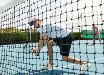 Man on serve with tenis racket and dressed in white t-shirt, black shorts and white shoes.
