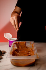 Confectioner's female hands sprinkle coconut flakes on chocolate cream