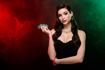 Chic classy rich wealthy lady professional poker player hold chips look for competitors over dark neon mist background