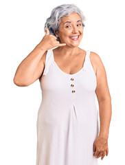 Senior woman with gray hair wearing casual clothes smiling doing phone gesture with hand and fingers like talking on the telephone. communicating concepts.