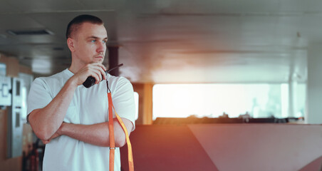 Deck Officer On The Bridge During Navigational Watch At Sea. Offshore Technician. Seafarer. Seaman. Navigator. A Man In The Wheelhouse Holding A Radio Station. Chief Officer On The Merchant Ship. © I am from Mykolayiv