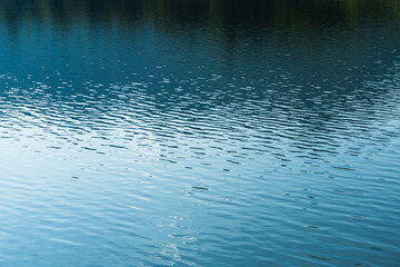 close up lake water background reflect the sky , blue and black water ripples texture