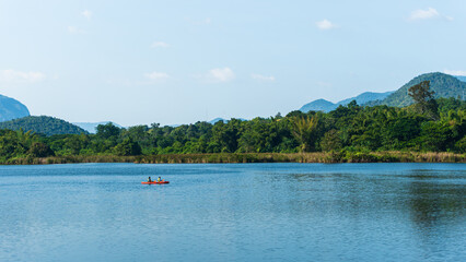 Fototapeta na wymiar Father and son kayaking on the lake somewhere in Kanchanaburi, Thailand, with beautiful green mountain view.