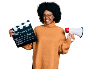 Young african american woman holding video film clapboard and megaphone winking looking at the camera with sexy expression, cheerful and happy face.
