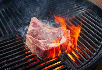 Barbecue dry aged wagyu prime rib beef steak grilled as close-up on a charcoal grill with fire and...