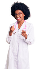 Young african american woman wearing doctor coat and stethoscope pointing fingers to camera with happy and funny face. good energy and vibes.