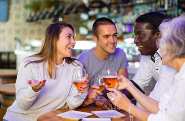 Spending time in bar. Four positive friends drinking beer in bar