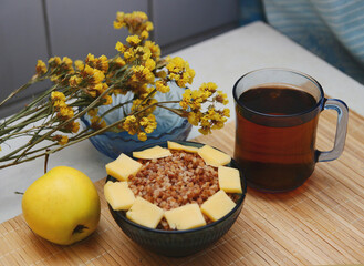 Homemade Ukrainian dinner - buckwheat with cheese, apples, tea. In blue and yellow colors.