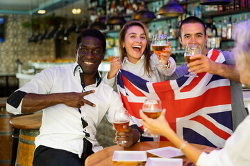 Happy diverse group celebrating Britain at a bar with beer