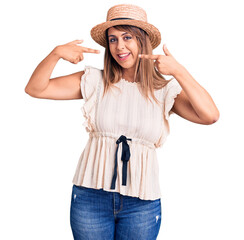 Young beautiful woman wearing summer hat and t-shirt smiling cheerful showing and pointing with fingers teeth and mouth. dental health concept.