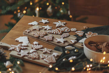 Christmas gingerbread cookies with icing on festive rustic  table with decorations against golden...