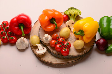 Wooden boards with different fresh vegetables on beige background