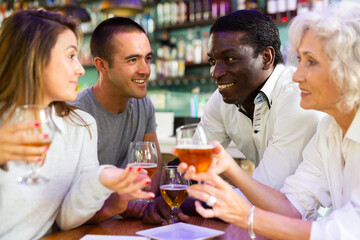 Happy diverse group having a conversation at a bar with beer