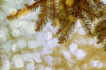Weihnachtlicher goldener Hintergrund mit Tannenzweige und glitzernden Schneeflocken
