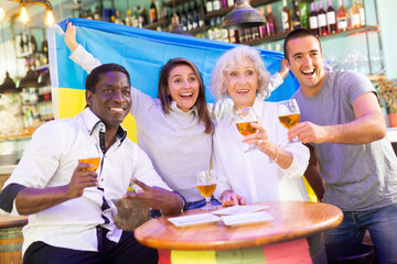 Happy diverse group celebrating Ukraine at a bar with beer
