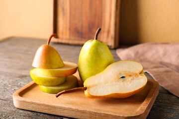 Wooden board with ripe pears on table