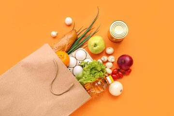 Paper shopping bag with different fresh products on orange background