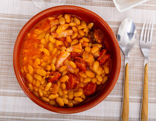 Appetizing bean stew served on plate with pieces of chorizo sausage..