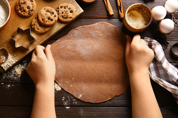 Woman with fresh dough preparing tasty Christmas gingerbread cookies on brown wooden background