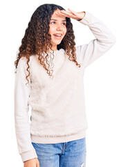 Fototapeta premium Beautiful kid girl with curly hair wearing casual clothes very happy and smiling looking far away with hand over head. searching concept.