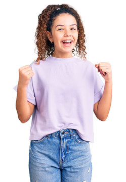 Beautiful kid girl with curly hair wearing casual clothes celebrating surprised and amazed for success with arms raised and open eyes. winner concept.