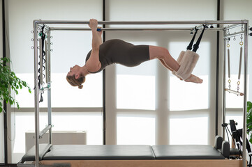 Pregnant woman doing pilates on a reformer. 