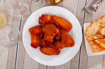 Delicious fried chicken wings dished up in a service plate on the laid restaurant table