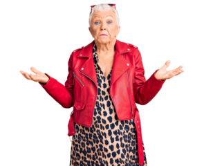 Senior beautiful woman with blue eyes and grey hair wearing a modern style with a red leather jacket clueless and confused expression with arms and hands raised. doubt concept.
