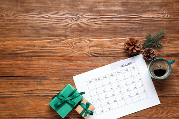 Paper calendar for January 2024, gift boxes, cup of coffee and pine cones on wooden background