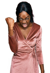 Obraz na płótnie Canvas Young african american woman wearing sexy party dress angry and mad raising fist frustrated and furious while shouting with anger. rage and aggressive concept.
