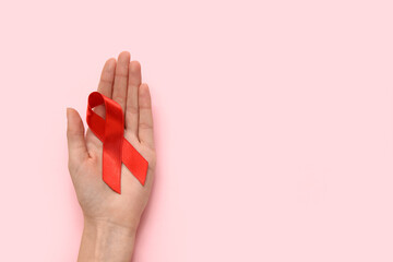Woman with red ribbon on pink background. AIDS Day concept