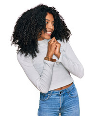 Young african american girl wearing casual clothes laughing nervous and excited with hands on chin...