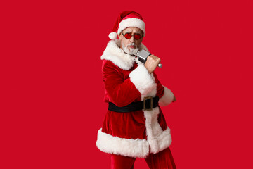 Santa Claus in sunglasses with microphone singing on red background
