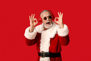 Santa Claus in headphones showing OK gesture on red background