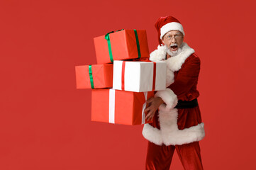 Shocked Santa Claus with many gift boxes on red background