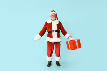 Santa Claus in glasses with gift box on blue background