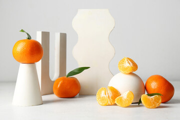 Decorative podiums with sweet mandarins on white background