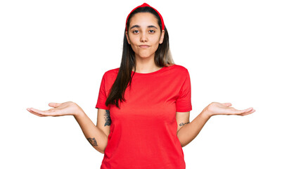 Young hispanic woman wearing casual clothes clueless and confused expression with arms and hands...