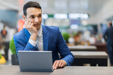 Thoughtful businessman working on laptop at airport