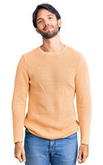 Handsome hispanic man wearing casual sweater relaxed with serious expression on face. simple and natural looking at the camera.