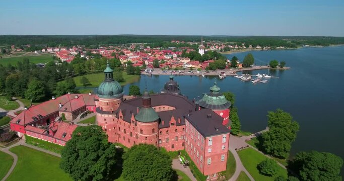 Aerial Shot Of Historic Castle By Lake In City While Drone Flying On Sunny Day - Mariefred, Sweden