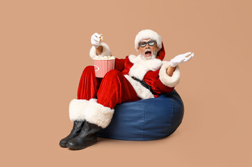 Shocked Santa Claus in 3D glasses with bucket of tasty popcorn on brown background