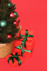 Fototapeta na wymiar Small Christmas tree with gifts on red background
