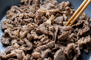 牛肉(切り落とし)をフライパンで炒める調理シーン。
